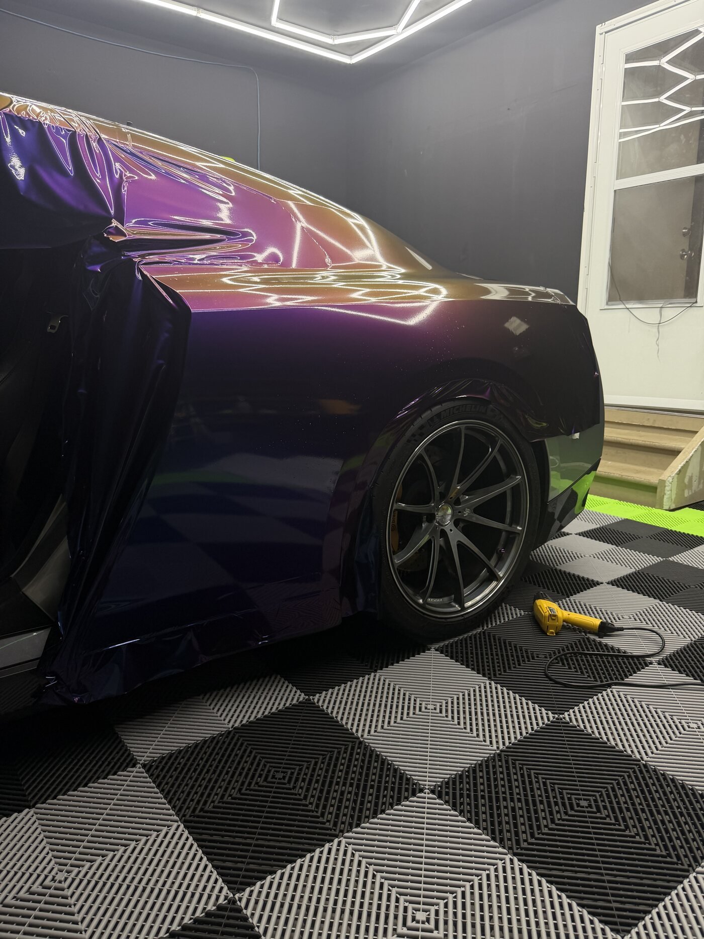 Rushing Riptide color-shift film being applied to the GT-R's rear quarter panel, mid-install