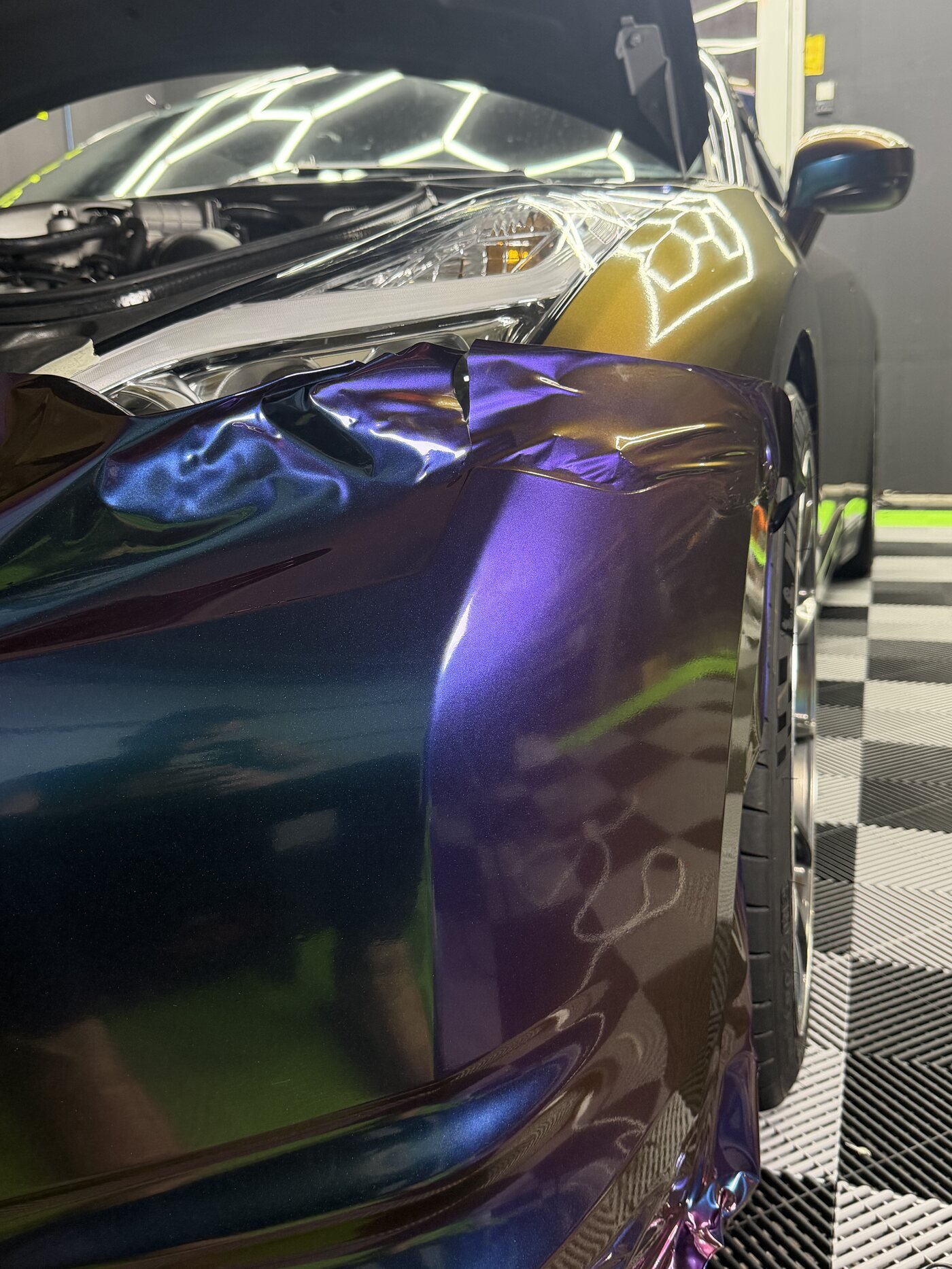 Film being worked around the GT-R's front fender and headlight