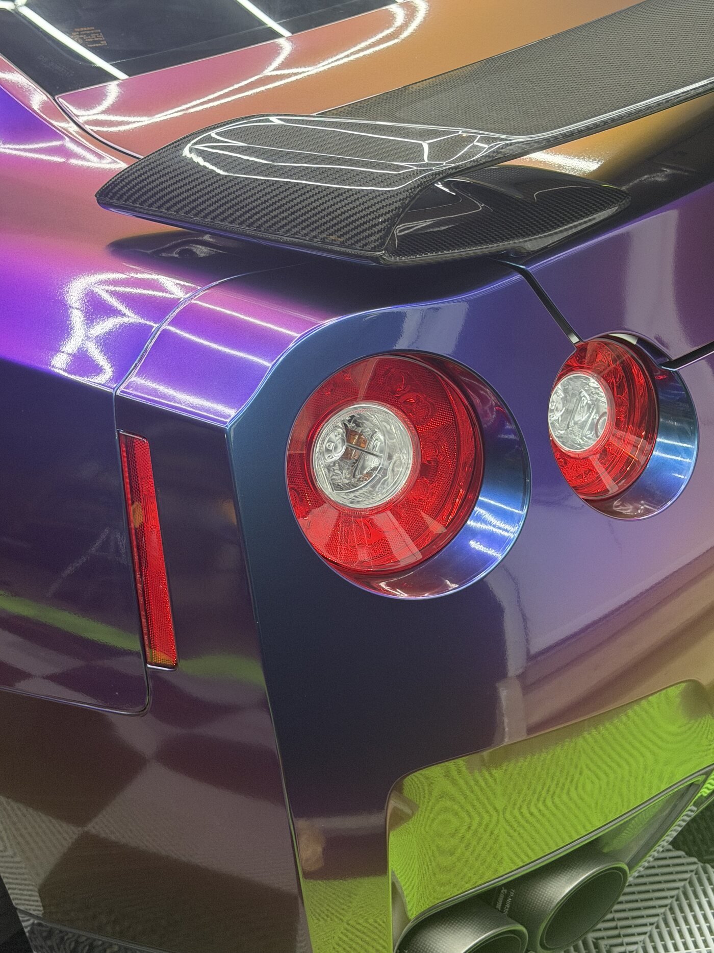 Close-up of the GT-R's taillight and carbon spoiler against the color-shift wrap