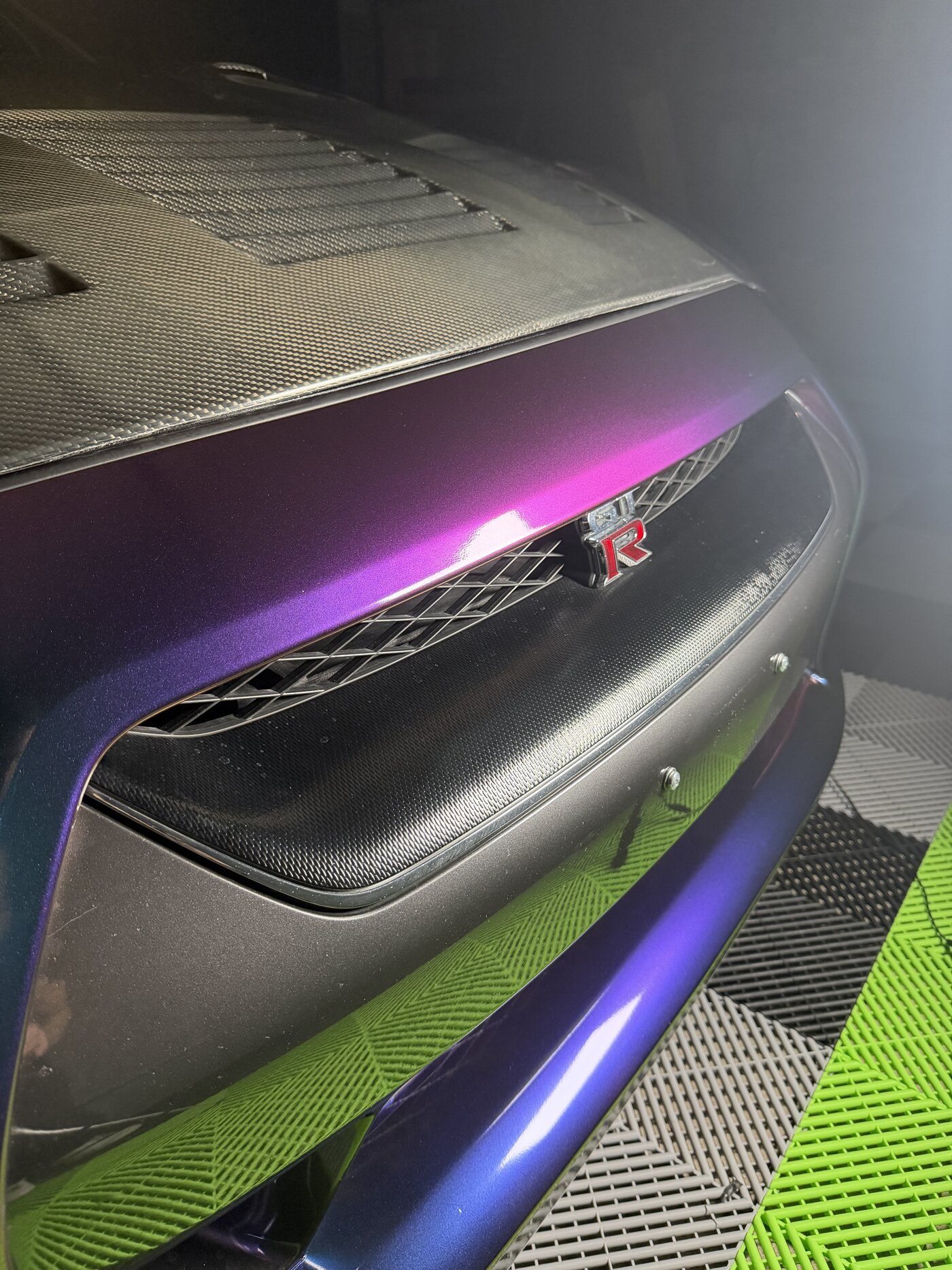 Close-up of the GT-R badge and front grille against the color-shift wrap