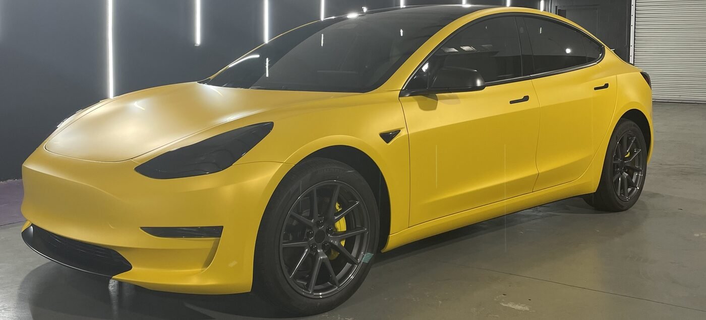 Tesla Model 3 wrapped in satin yellow, front three-quarter view