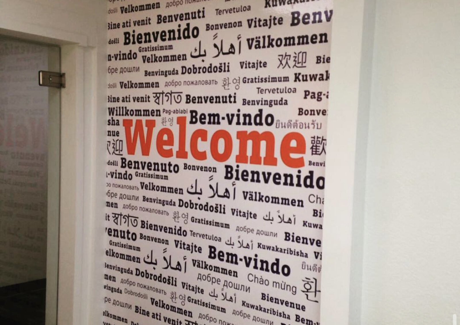 Multilingual Welcome wall graphic in an office hallway